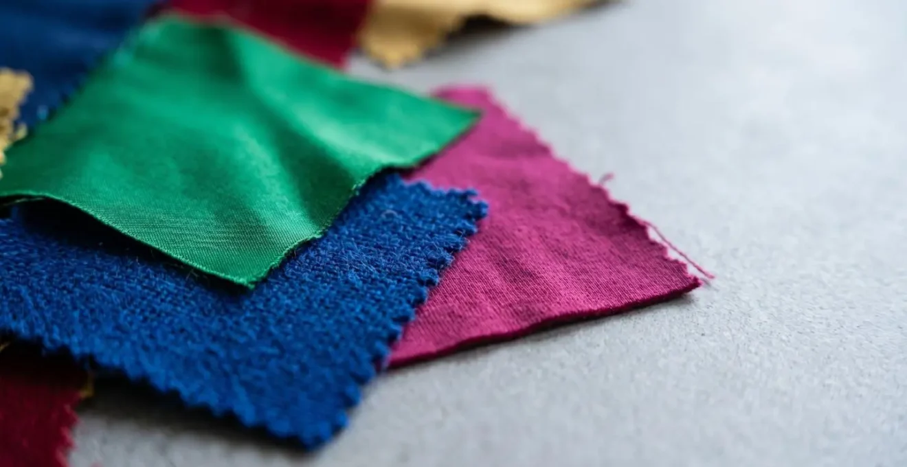 Macro detail of vibrant fabric swatches under cool fluorescent office lighting showing color temperature effects