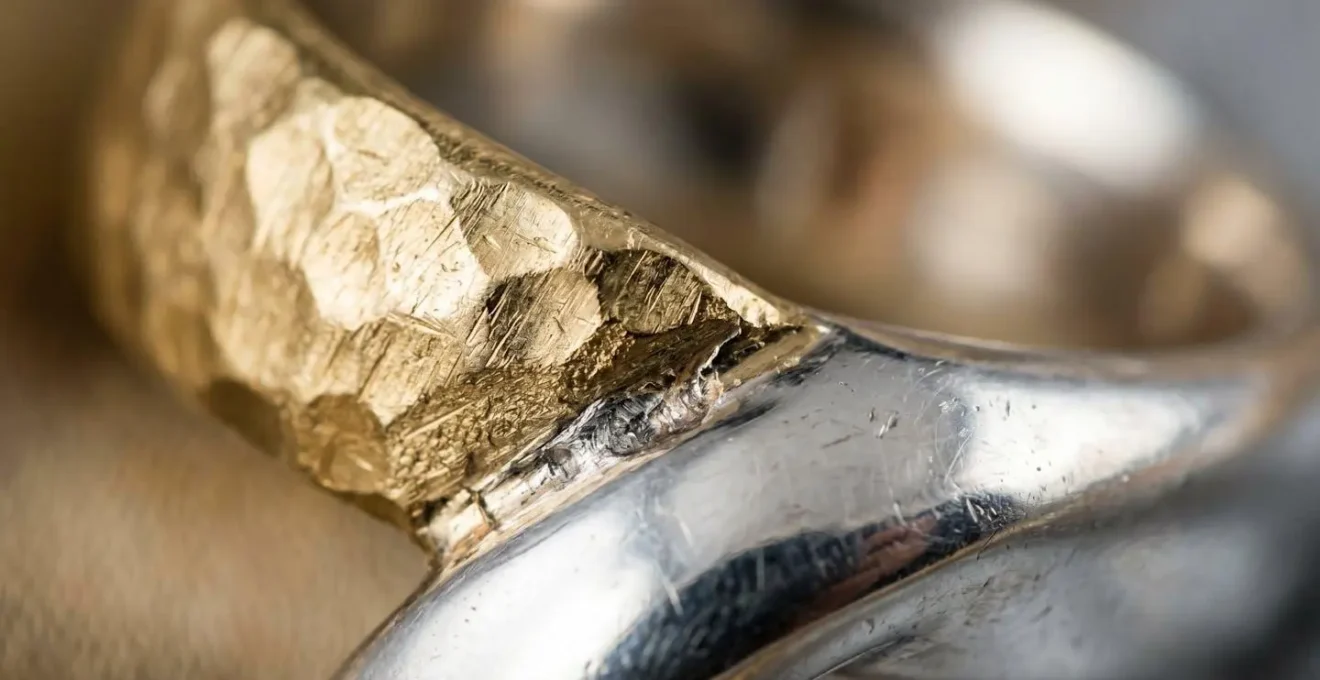 Close-up detail of mixed gold and silver jewelry showing different textures and finishes