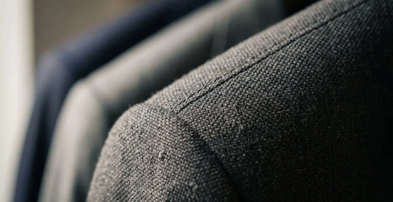 Close-up detail of structured professional garment showing tactile fabric texture and precise tailoring representing confidence-building ritual