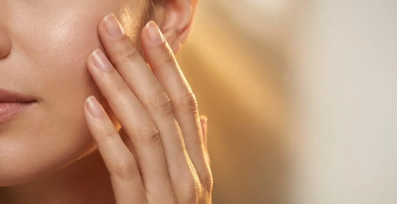 Symbolic representation of sun protection showing human hand applying invisible protective layer with golden sunlight rays diffused in background