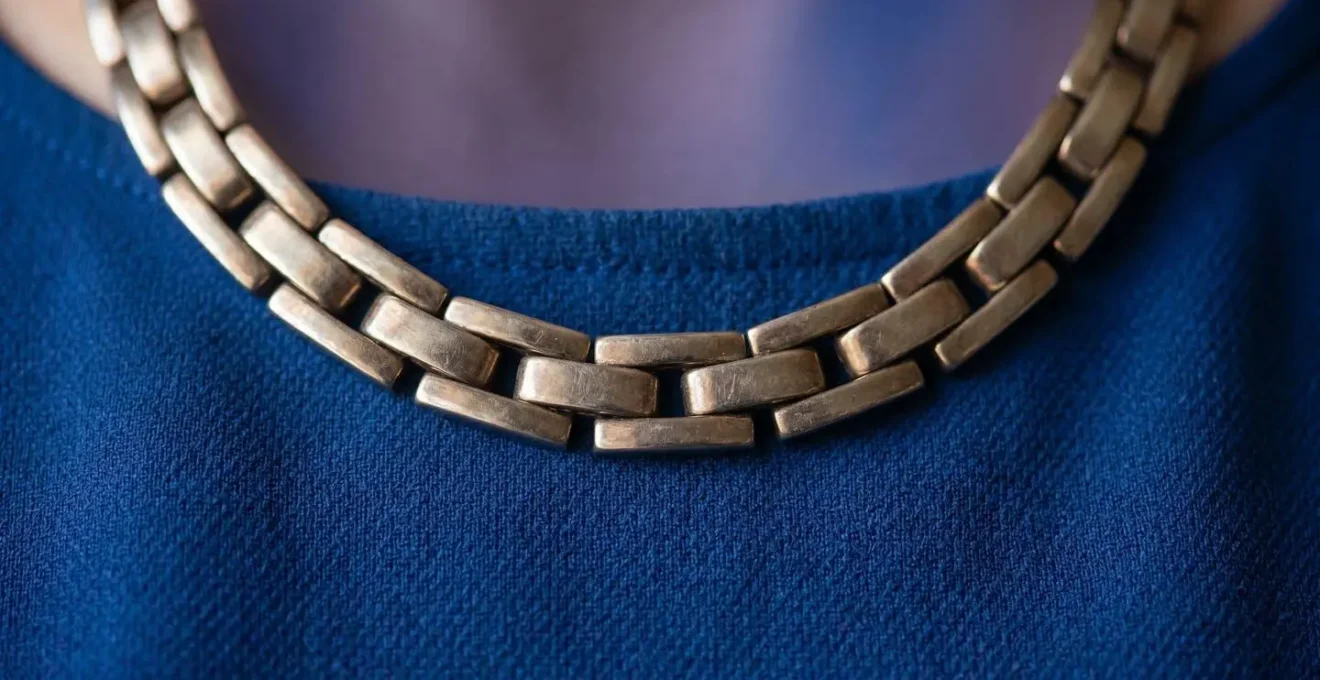 Close-up detail of professional necklace creating visual anchor point near neckline, demonstrating how jewelry directs viewer attention during video calls